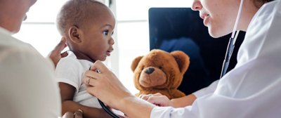 Pediatrician holds stethoscope up to a baby 