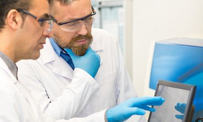 Vertical cropped shot ot two experienced mature lab technicians talking while conducting experiments at the modern laboratory working on a computer. Medical researchers at work