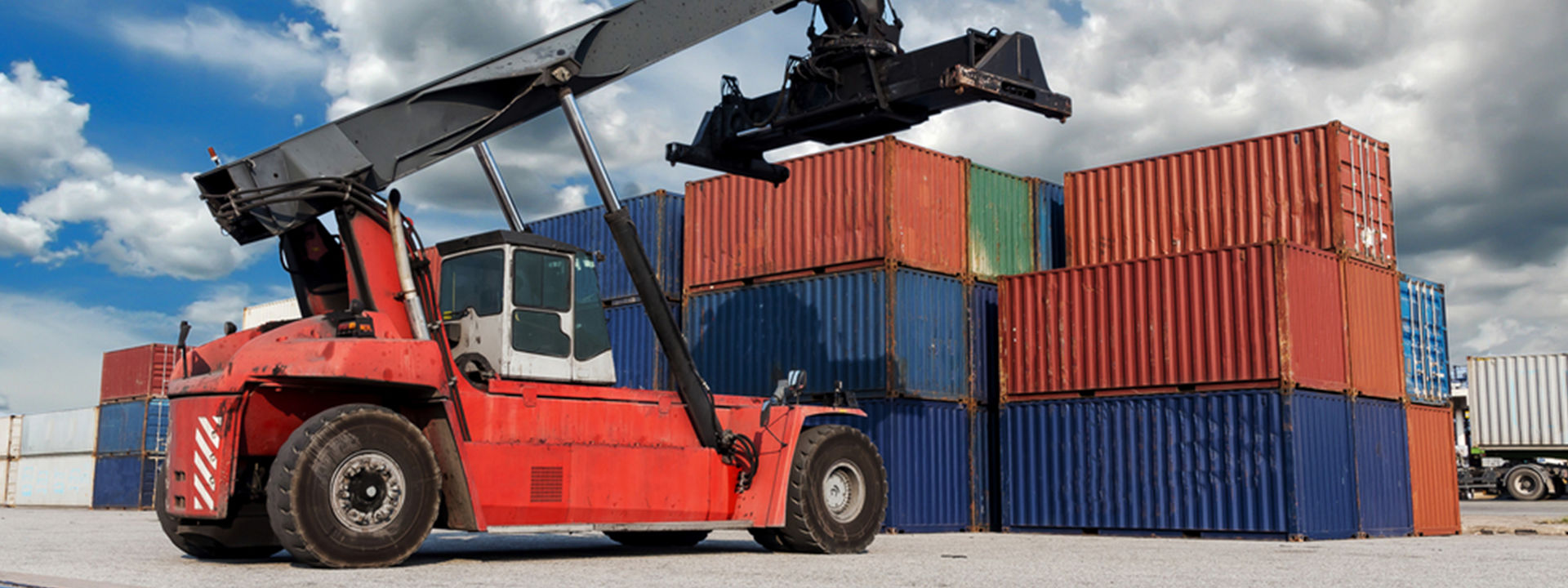 A forklift equipped with Bridgestone off-the-road tyres is moving shipping containers across a large industrial port
