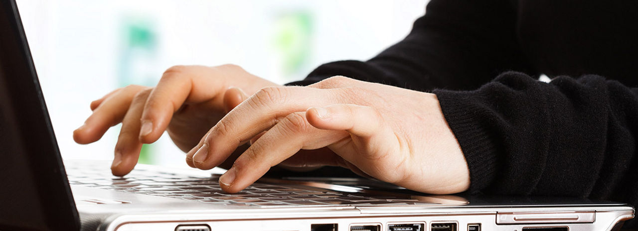 Deze afbeelding toont een close-up van handen die op een toetsenbord typen.