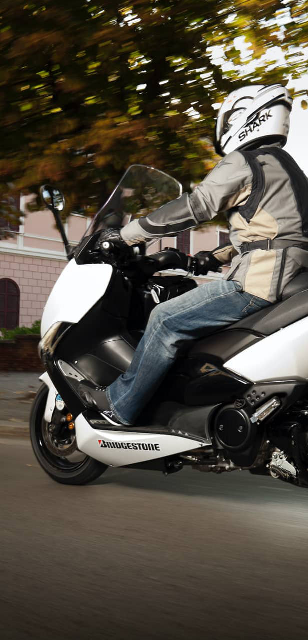 This image shows a close-up view of a rider on a scooter with Bridgestone tyres