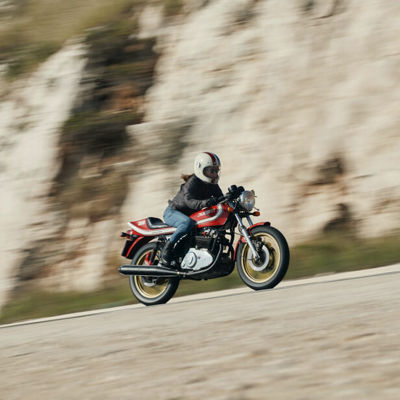 Šioje nuotraukoje matome motociklininkę, važiuojančią per kraštovaizdį su „Bridgestone Battlax BT-45“ padangomis.