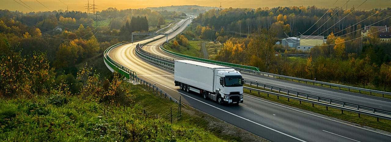 A képen egy festői országút és egy áruszállító flotta a Bridgestone hosszútávú abroncsaival haladó járműve látható.