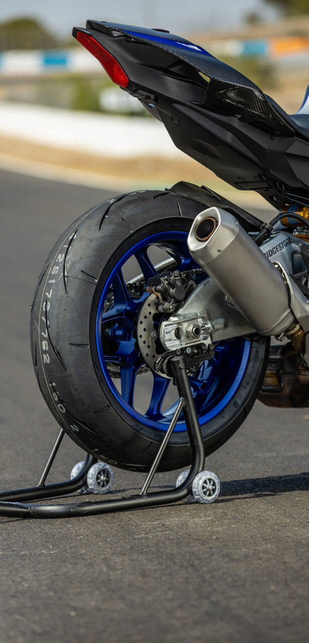 This image has a focus on a Bridgestone Sport motorcycle tyre.