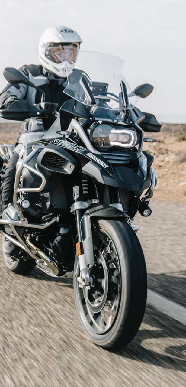 This image shows a front view of a motorcyclist riding with Bridgestone adventure tyres
