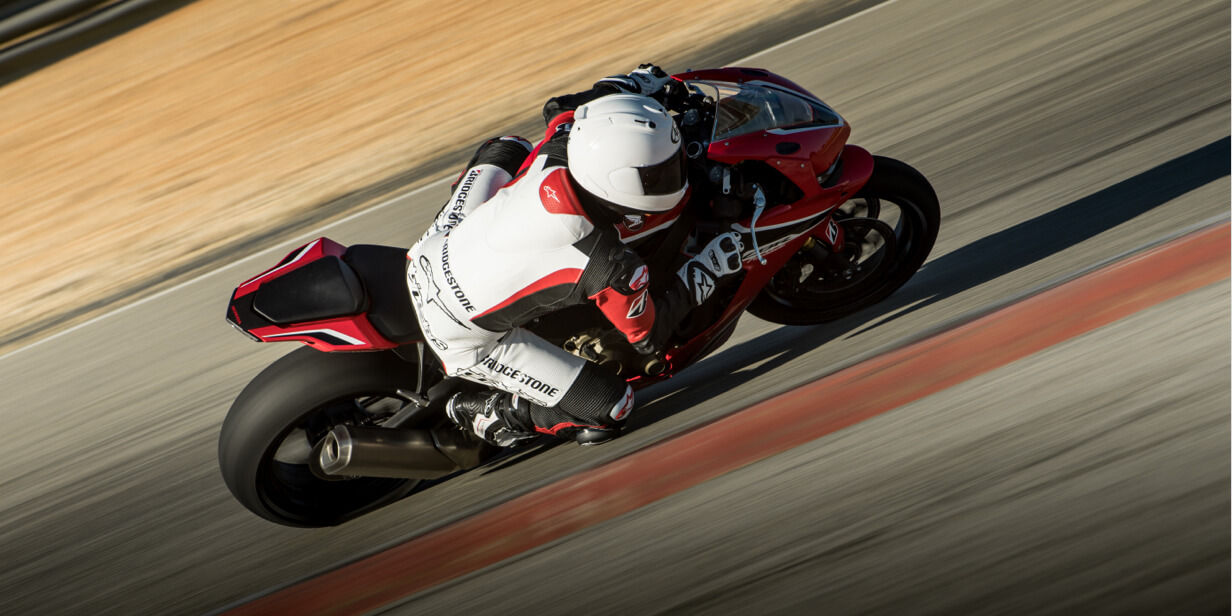 On this photograph we see a motorcycle racer cornering with Bridgestone tyres on a race track at high speed.
