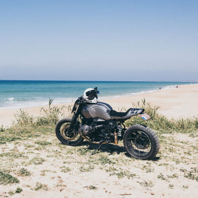 This image shows a motorcycle with a view off the sea with Battlax Adventurecross Scrambler AX41S Bridgestone tyres.