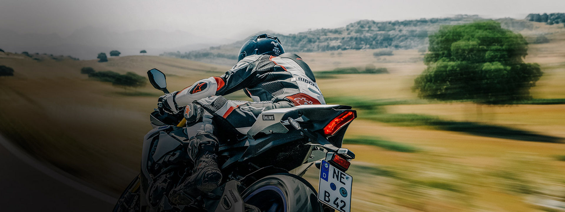 Esta imagen muestra a un motociclista conduciendo su motocicleta con neumáticos deportivos Bridgestone en una carretera.