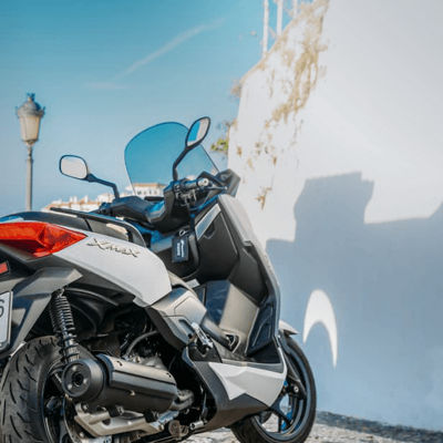 This image shows a scooter with Bridgestone tyres near a city wall