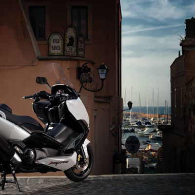 This image shows a scooter with Bridgestone tyres on a picturesque city road