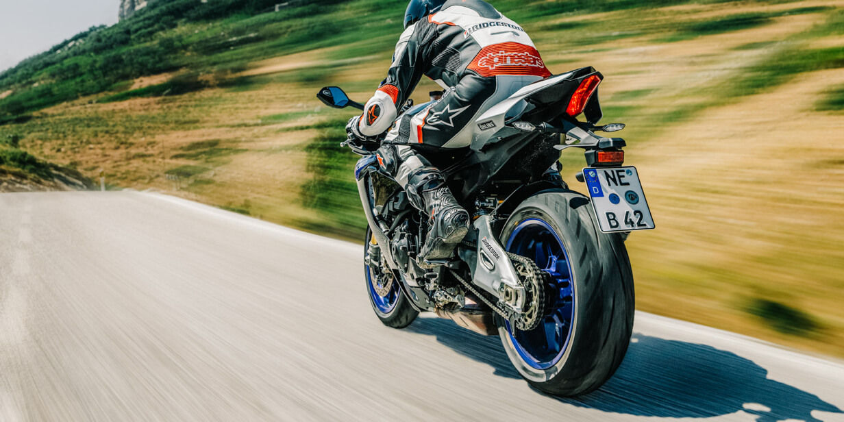Na tej sliki je prikazan športni motocikel z Bridgestonovimi pnevmatikami med vožnjo po cesti.