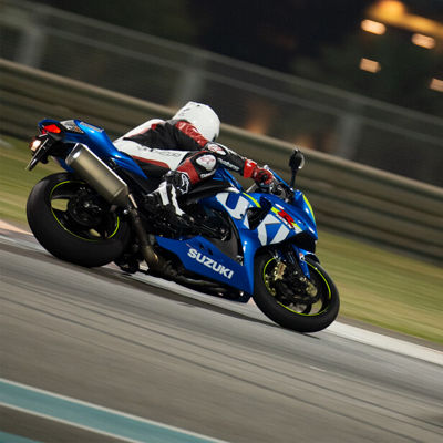 This is a picture of a Suzuki motorcycle racing on the circuit at night with Bridgestone tyres.
