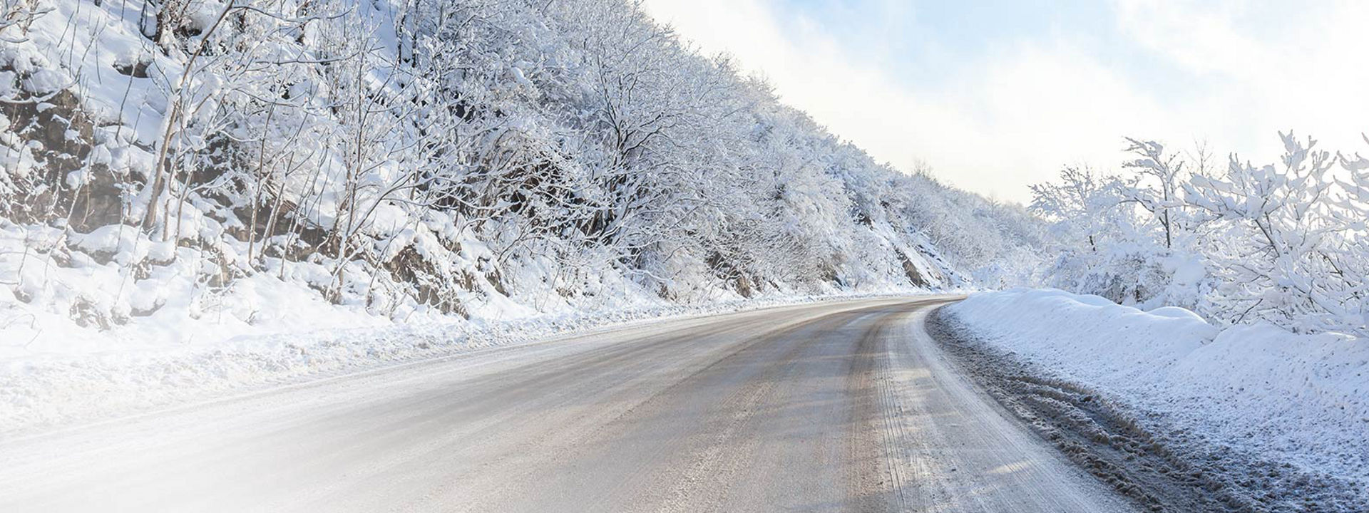 Esta imagem mostra uma estrada de inverno coberta de neve com marcas de pneus de Inverno para camião da Bridgestone.
