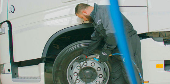 Denna bild visar en operatör som kontrollerar lufttrycket på ett däck i en fordonspark.