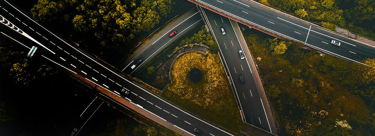 Vue plongeante sur des autoroutes qui se croisent et les voitures qui y circulent.