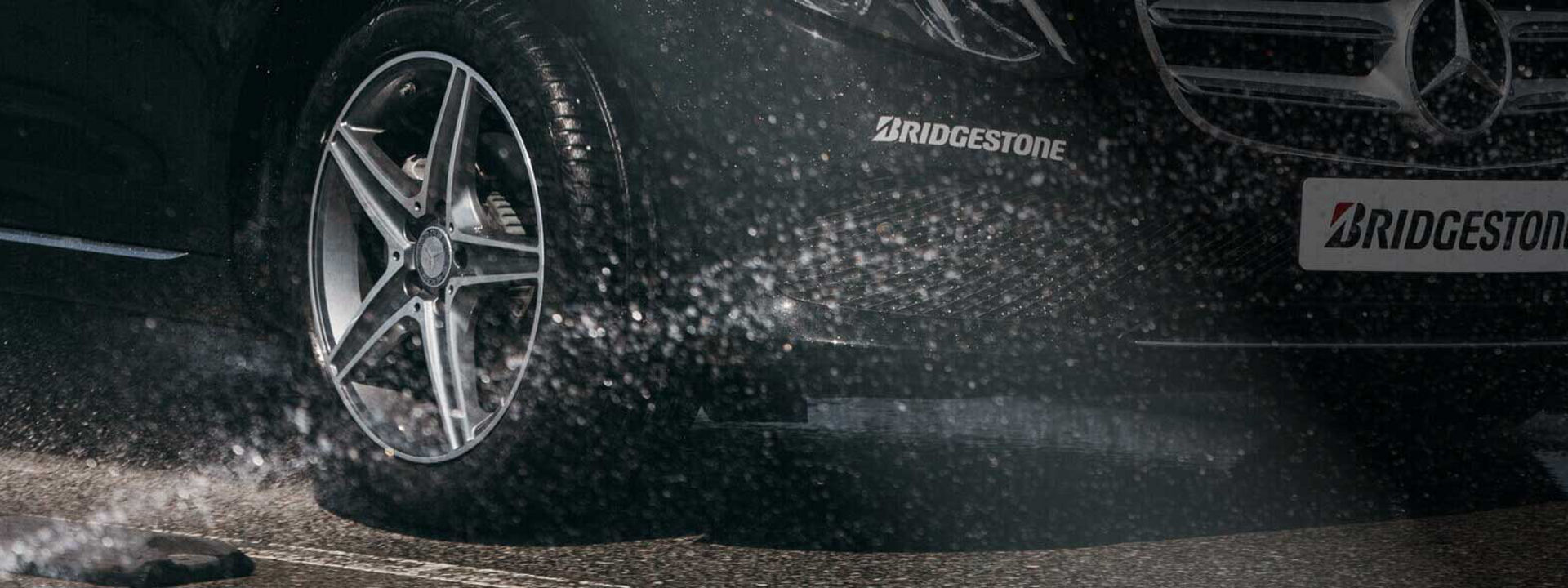 This image is a close-up of a Bridgestone Turanza tyre driving through wet conditions