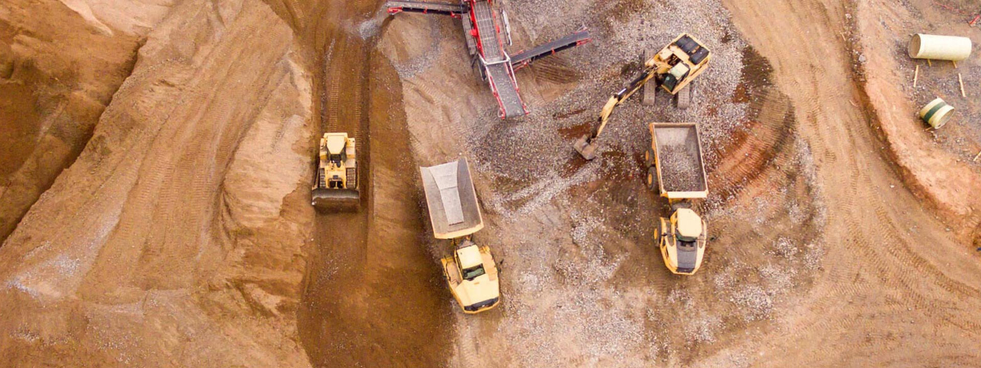 Multiple articulated dump trucks working at a large construction site