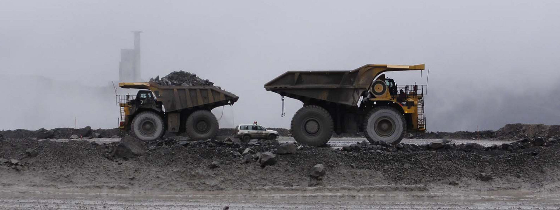 Quatre véhicules tout-terrain équipés de pneus Bridgestone travaillant dans une mine à ciel ouvert.