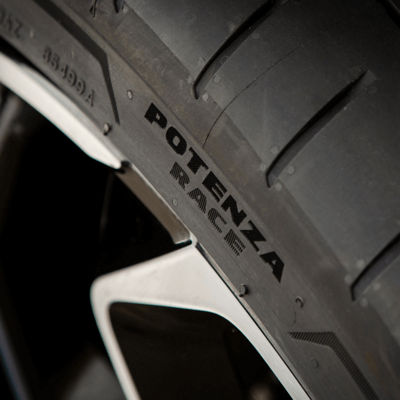 Una vista lateral de los neumáticos Potenza Race en las ruedas delanteras de un turismo de carreras.