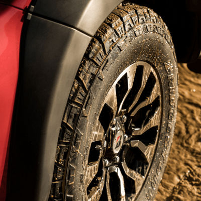 Close-up side view of a Dueler All-Terrain A/T002 tyre’s aggressive tread pattern design with rim, sipes and grooves.