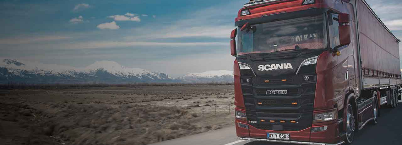 This image shows a Scania truck with Bridgestone tyres driving on a highway with mountains in the landscape. 