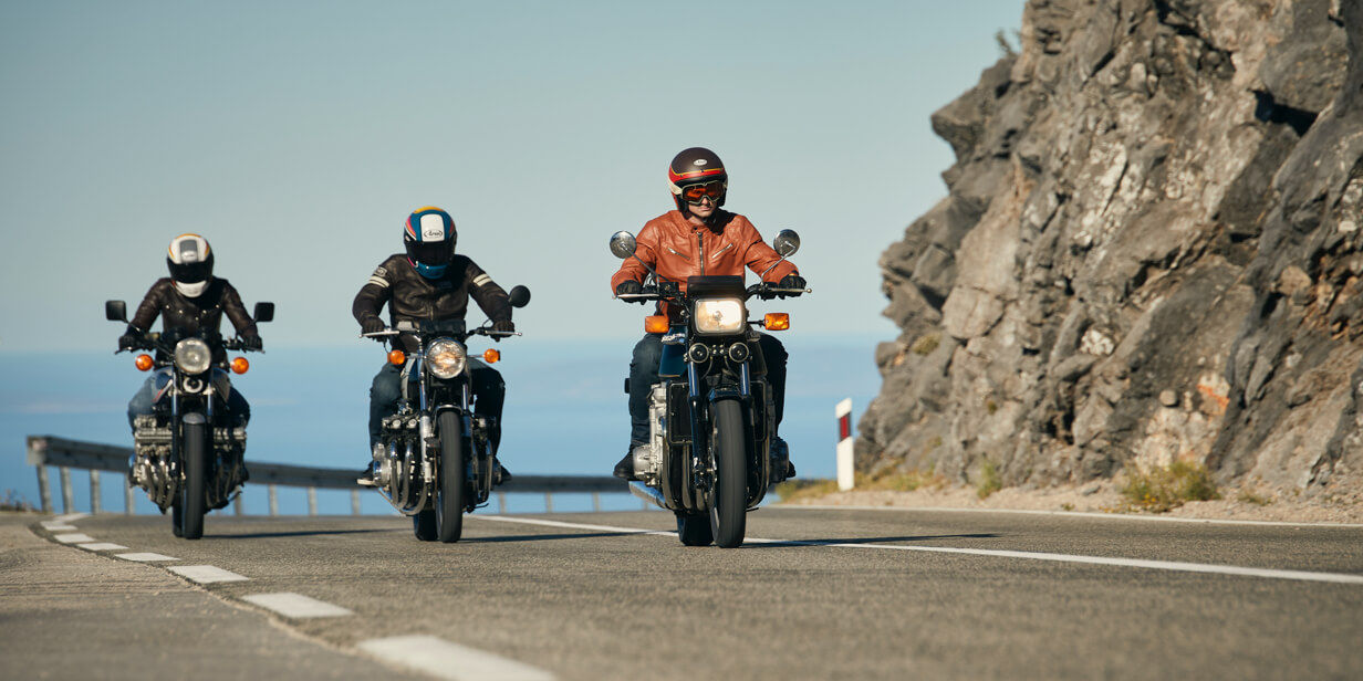 Trys motociklininkai patogiai keliauja vėjuotu keliu su „Bridgestone Battlax BT-45“ padangomis.