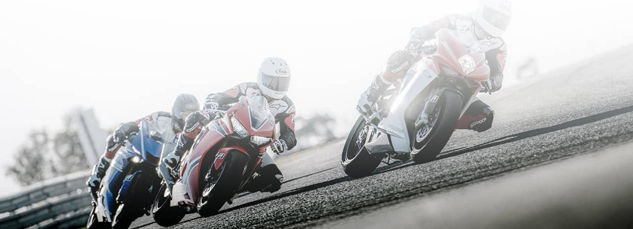 This image shows three motorcyclists cornering on a race track with Bridgestone Racing motorcycle tyres.