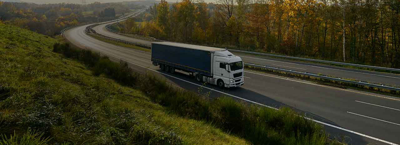 Denna huvudbild visar en lastbil körandes på en vacker motorväg.
