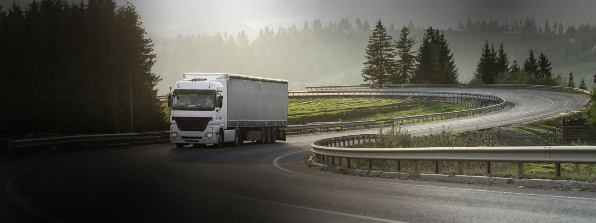 Zdjęcie przedstawia ciężarówkę poruszającą się po drodze regionalnej na uniwersalnych oponach ciężarowymi Bridgestone.