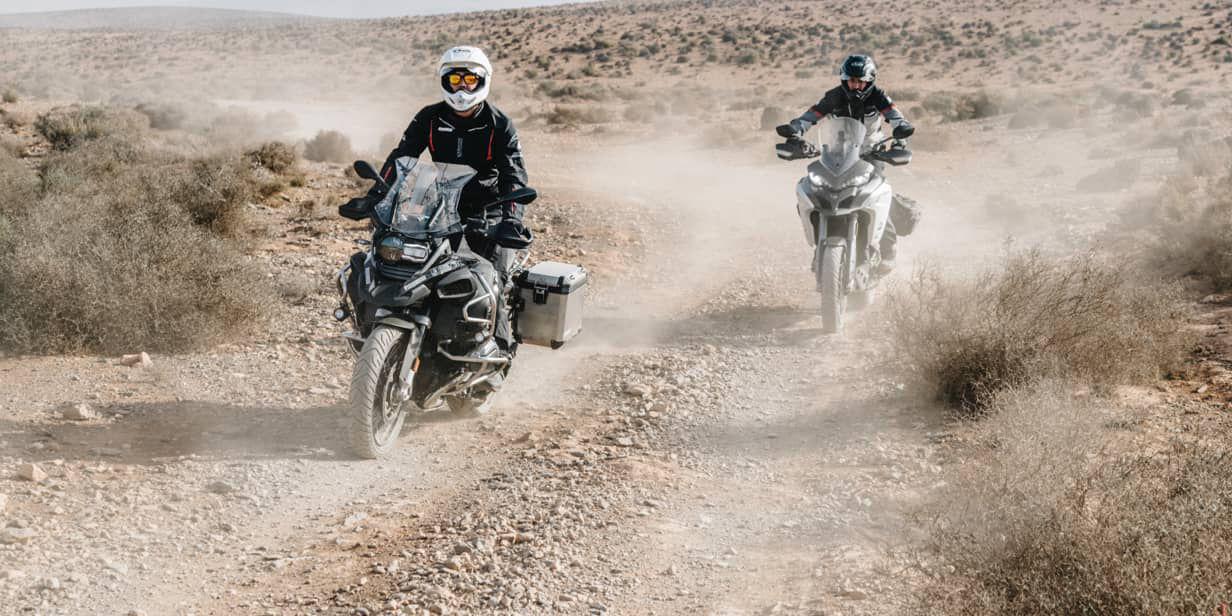 This image shows two motorcyclists riding in the desert with Bridgestone adventure tyres