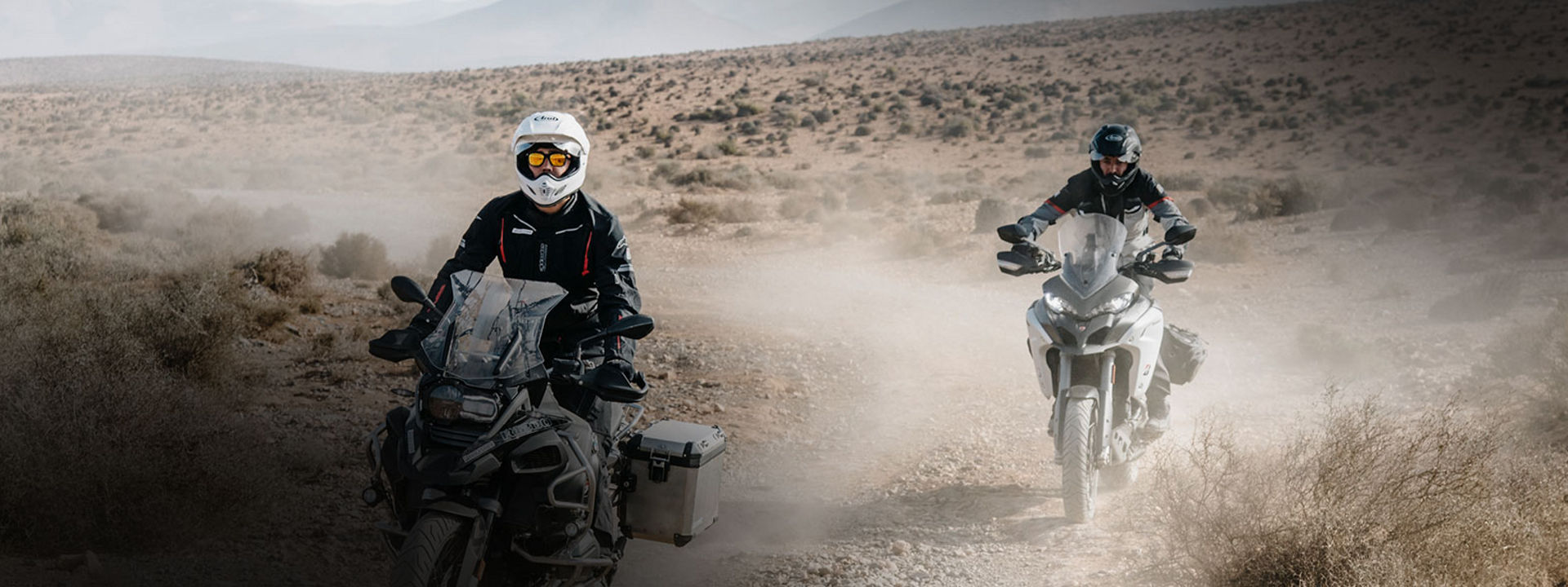 This image shows two motorcyclists using Bridgestone adventure tyres to explore a desert by motorcycle.