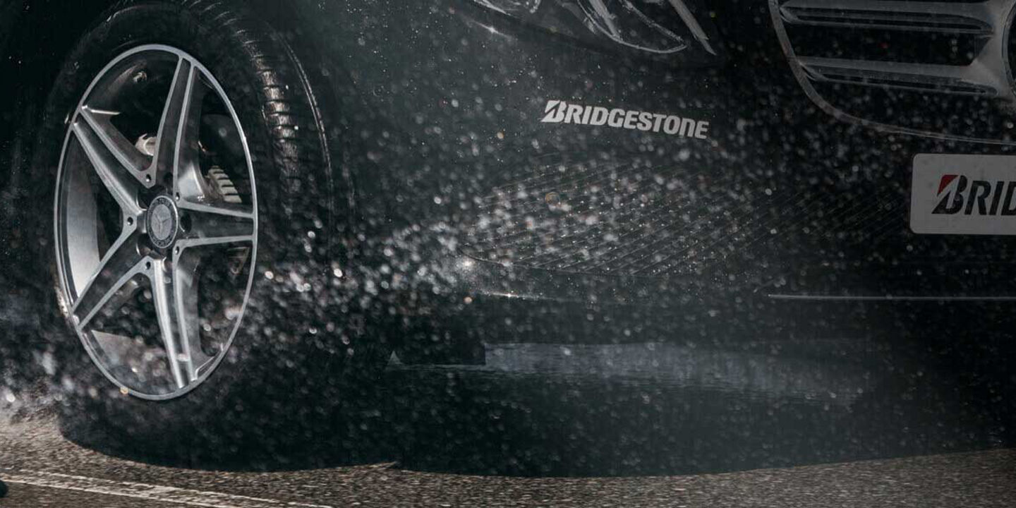 This image is a close-up of a Bridgestone Turanza tyre driving through wet conditions