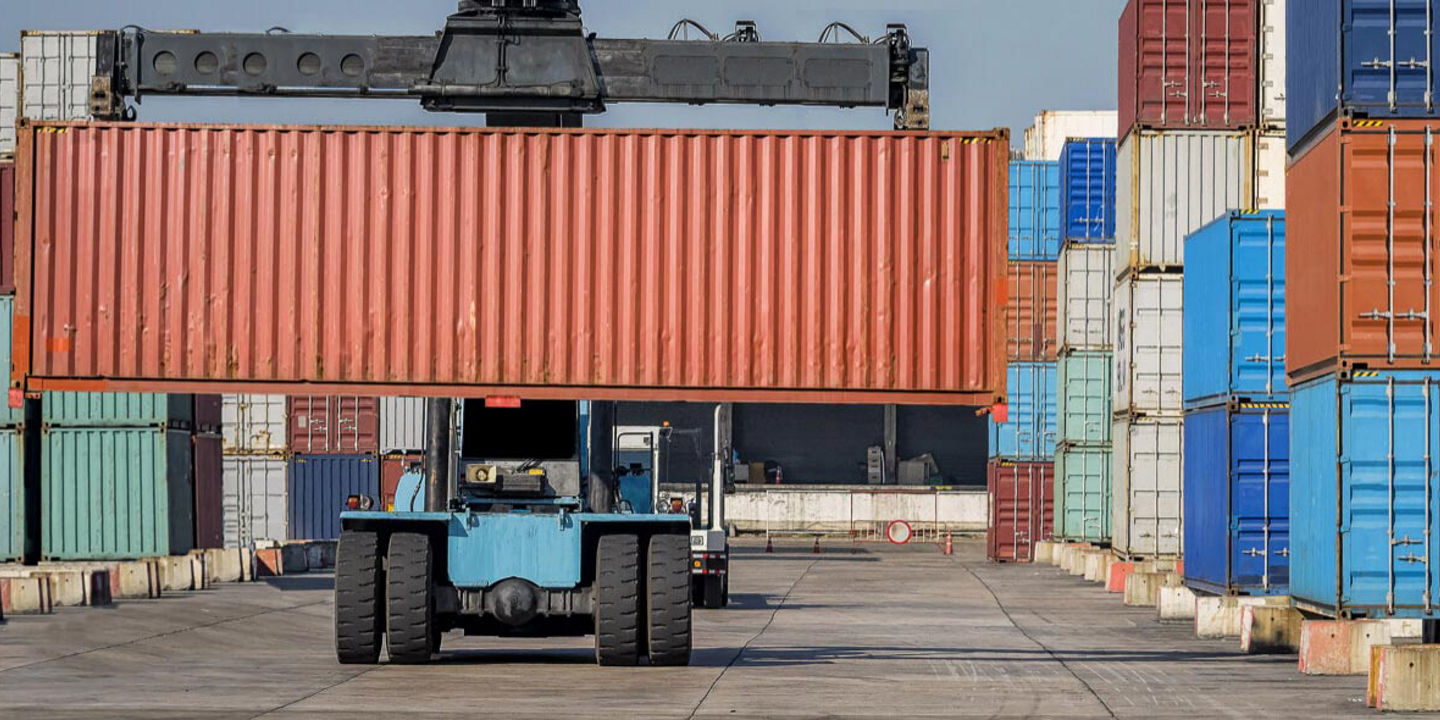 A forklift equipped with Bridgestone off-the-road tyres is moving shipping containers across a large industrial port