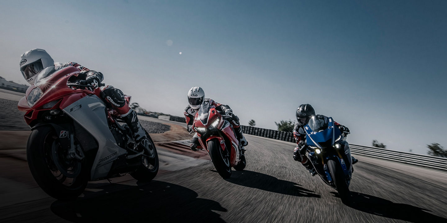 This image shows three motorcycle racers cornering with Bridgestone tyres on a race track at high speed. 