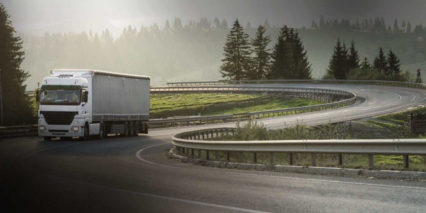 This image shows a long-haul truck driving on a regional road with Bridgestone versatile truck tyres.