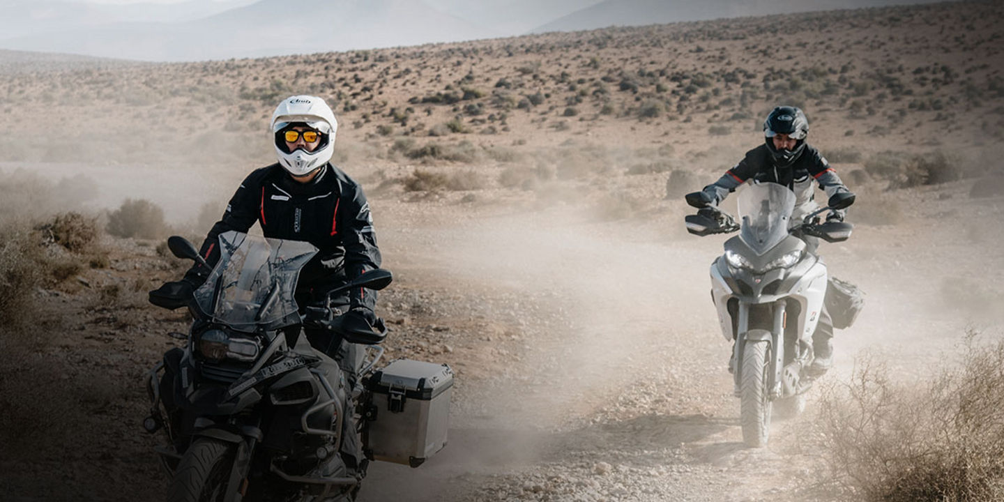 This image shows two motorcyclists using Bridgestone adventure tyres to explore a desert by motorcycle.