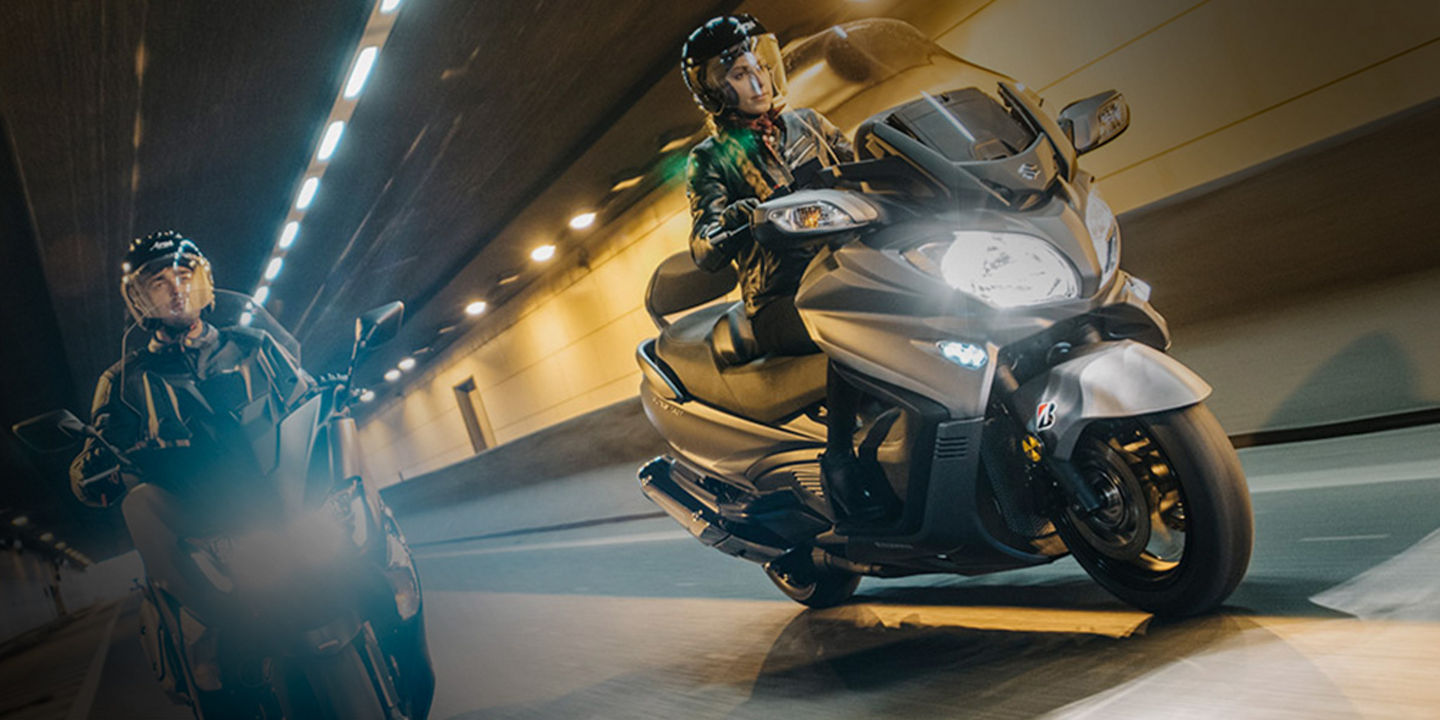 This image shows two riders on scooters using Bridgestone scooter tyres going through a tunnel. 