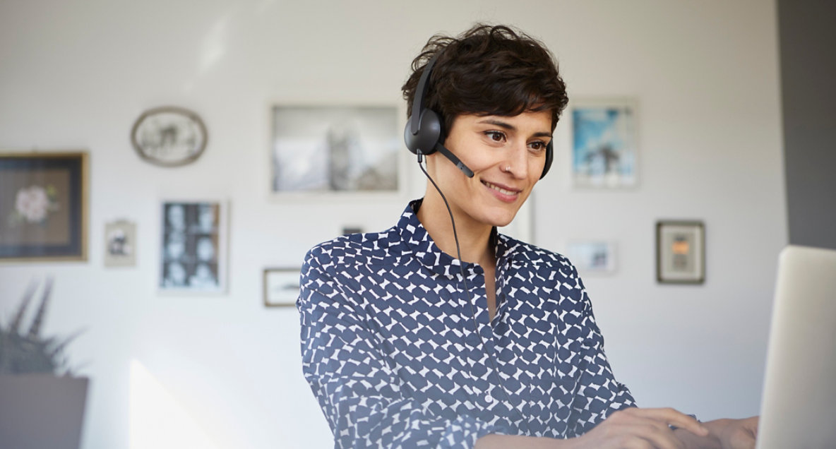 smiling-woman-at-home-with-headset-using-laptop