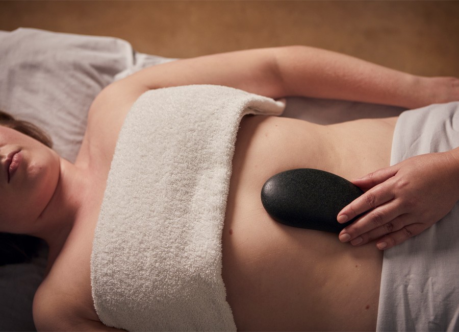 Woman laid on her back with a smooth stone on her stomach.