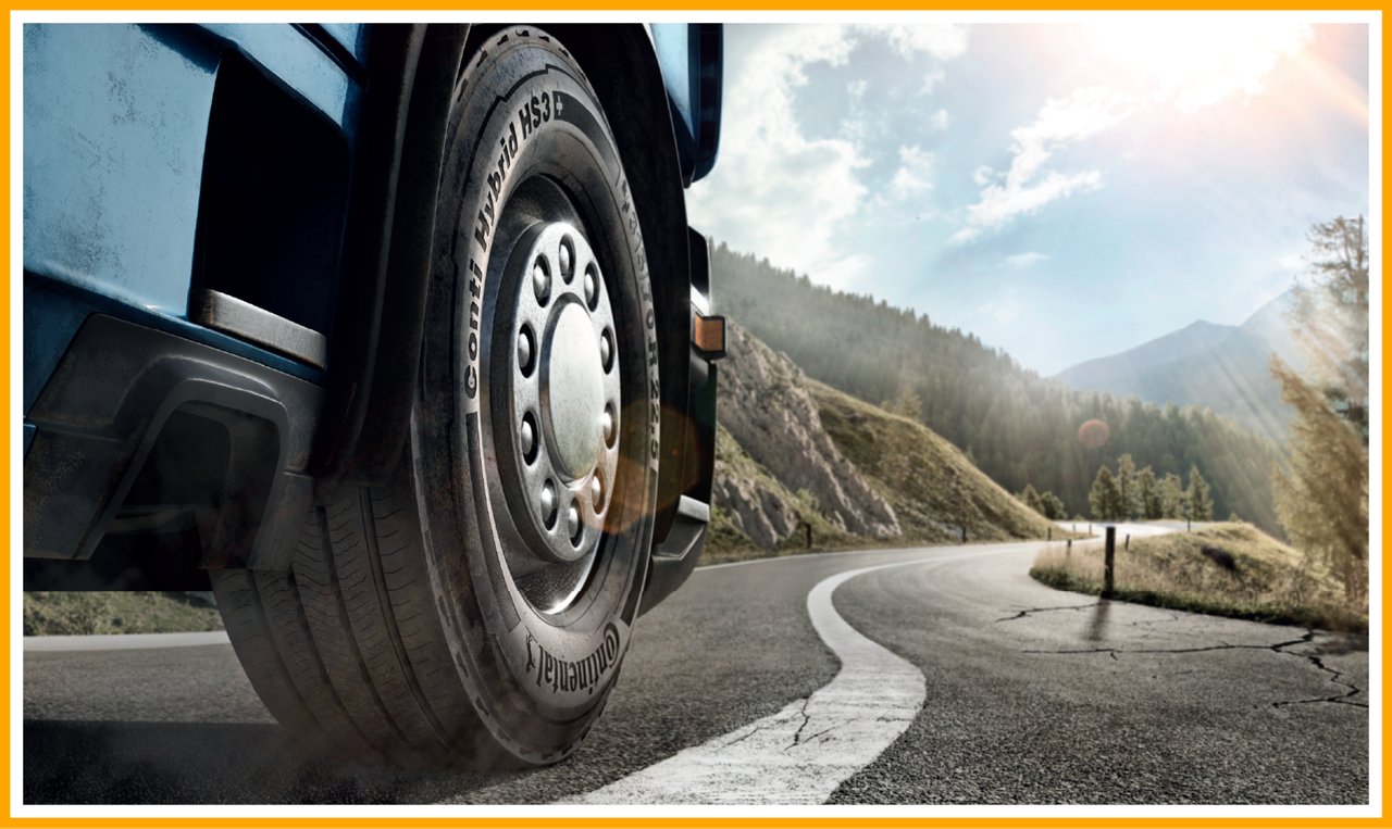Close-up of a Continental 'Conti Hybrid HS3' truck tire on a winding mountain road.