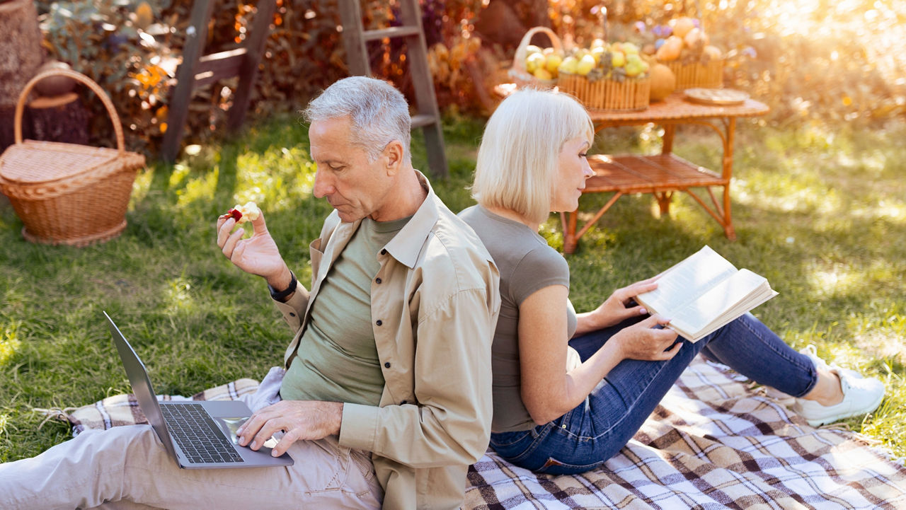 Couple Enjoying a Quiet Afternoon in the Garden With a Laptop and a Book; Shutterstock ID 2703425001; purchase_order: sito; job: ; client: ; other: 