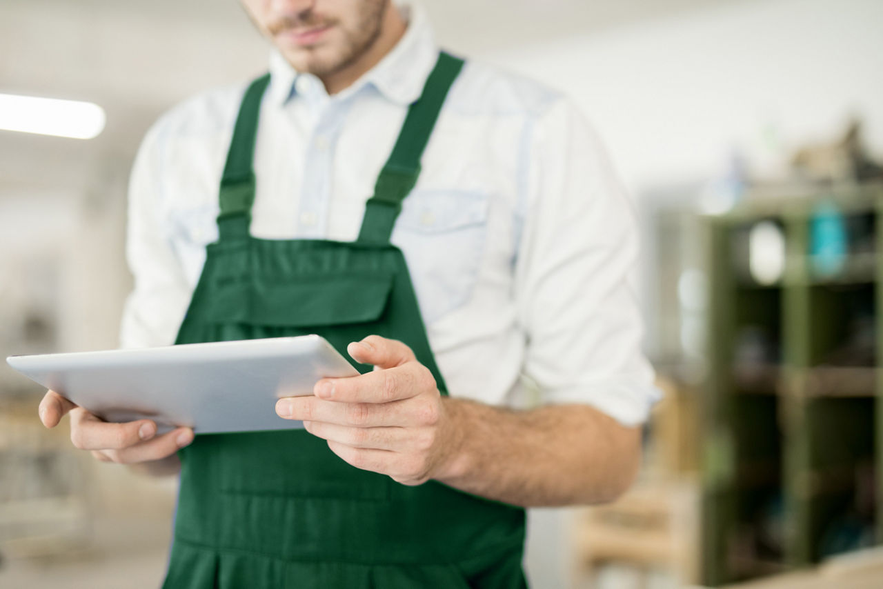 Young man in workwear holding touchpad while searching for ideas for new technical project; Shutterstock ID 1202629603; purchase_order: sito; job: ; client: ; other: 