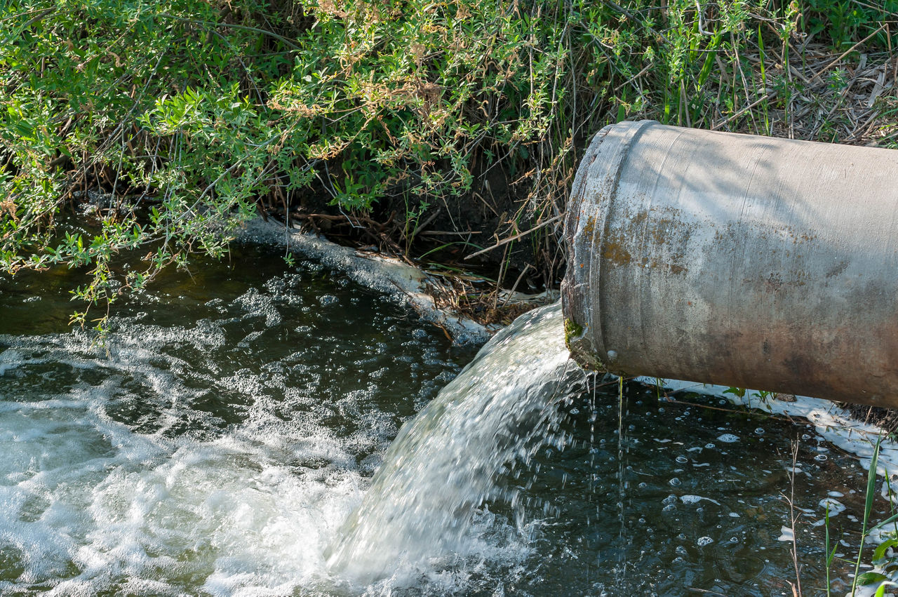 Concrete pipe transporting the poluted river in to a small pond.; Shutterstock ID 1084001093; purchase_order: -; job: -; client: -; other: