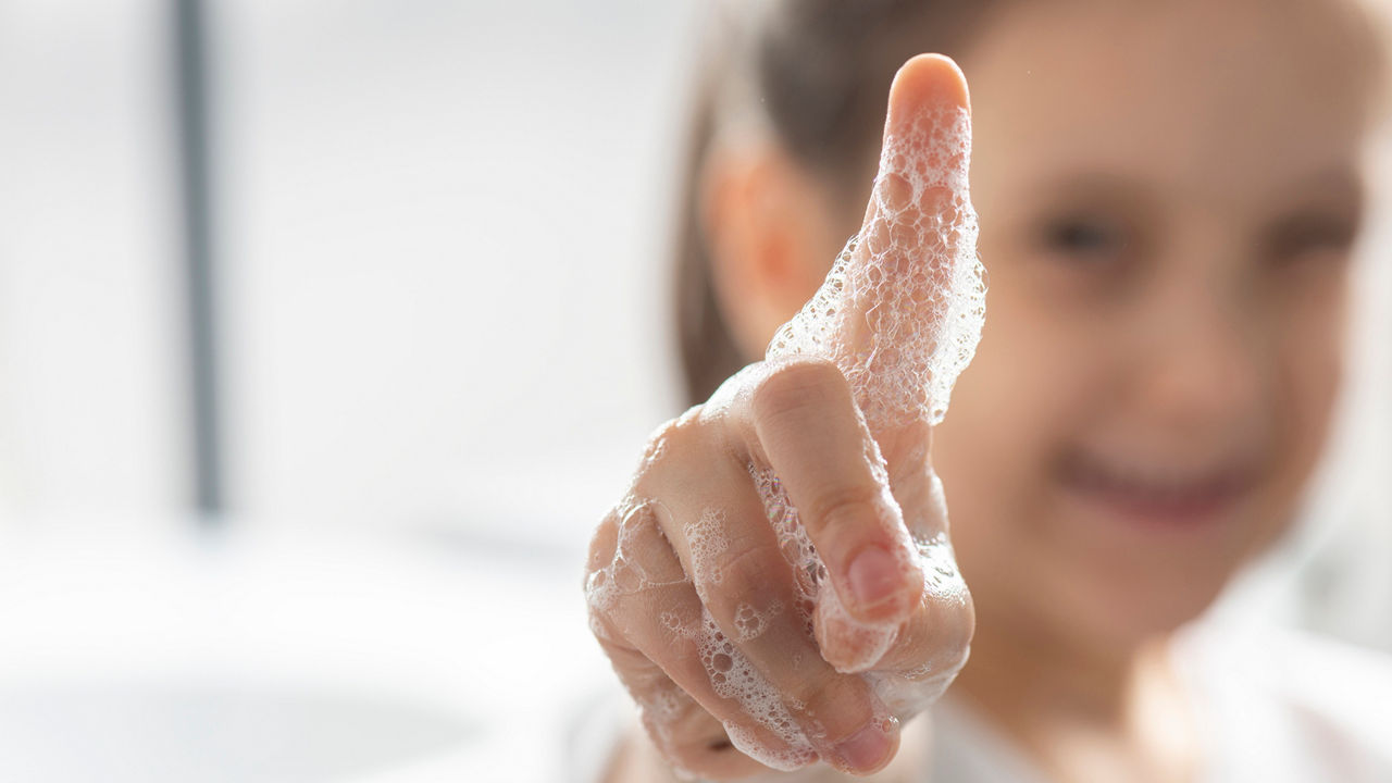 Little girl is showing her soapy finger.