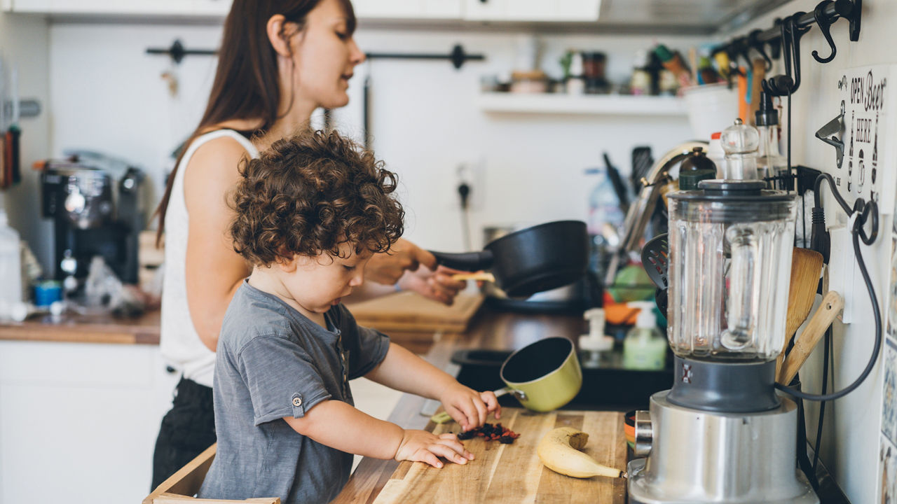 Mother and toddler boy cooking at home in the kitchen