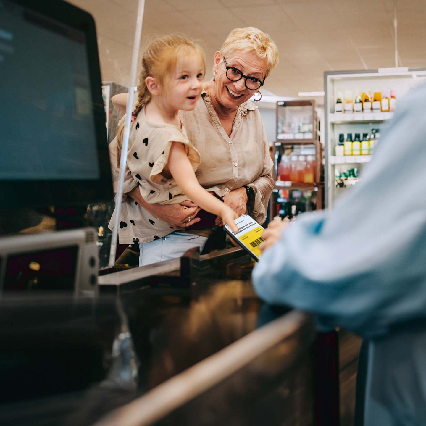 Oma und Enkelin zahlen mit Bargeld-Code an einer Kasse