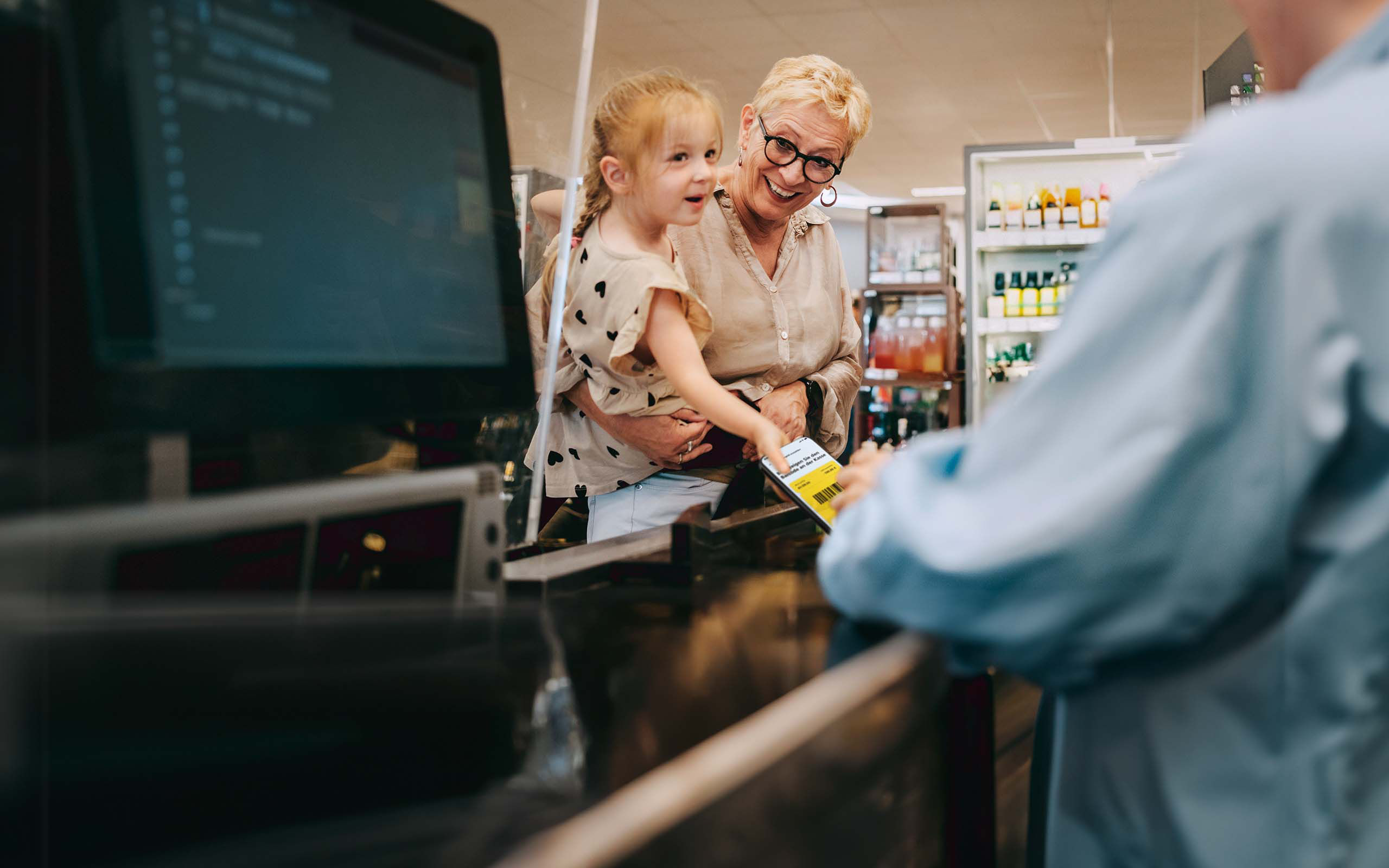 Oma und Enkelin zahlen mit Bargeld-Code an einer Kasse