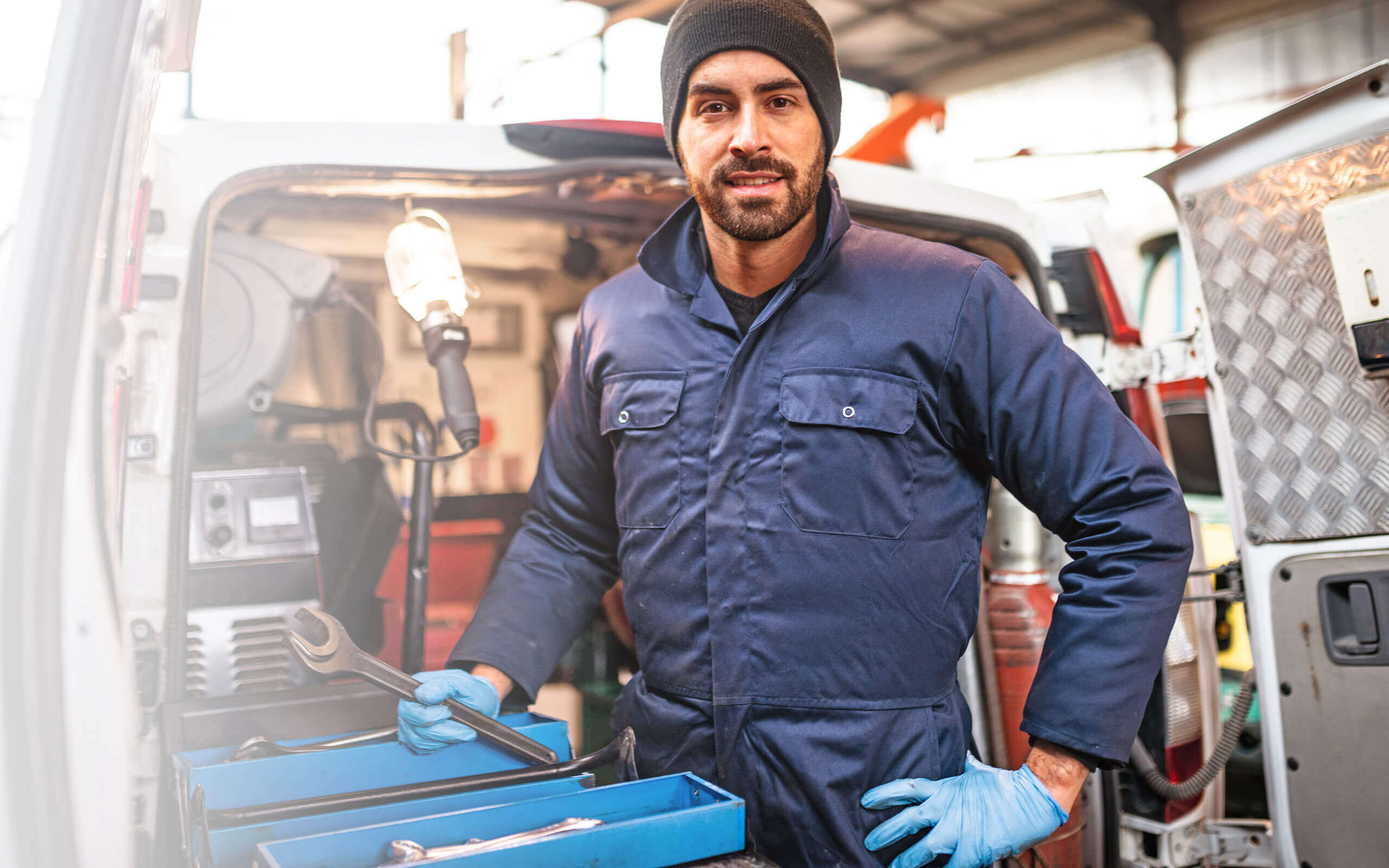 Ein Mechaniker steht vor einem Werkstattwagen mit Werkzeug