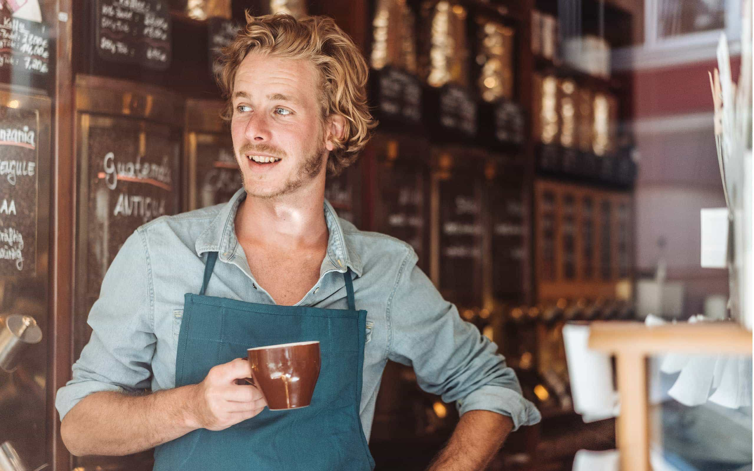 Ein Kaffeeröster verkostet zufrieden seine Kreation.