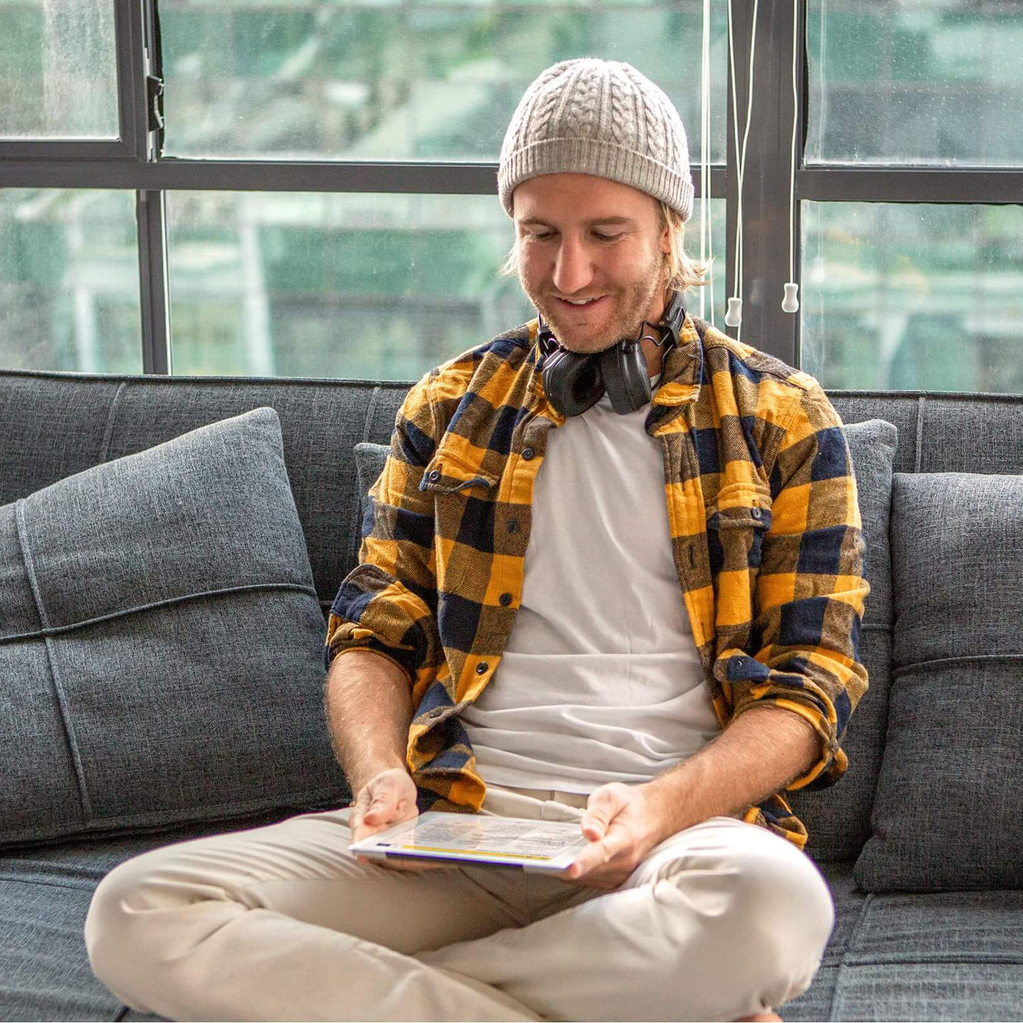 Ein junger Mann sitzt auf der Couch und schaut auf sein Tablet